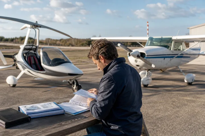 ULM et avionnette légère stationnés sur un aérodrome, avec des documents et coûts de propriété sur une table