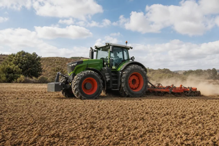 Landwirtschaftlicher Traktor bei der Arbeit mit einem Anbaugerät auf einer Anbaufläche